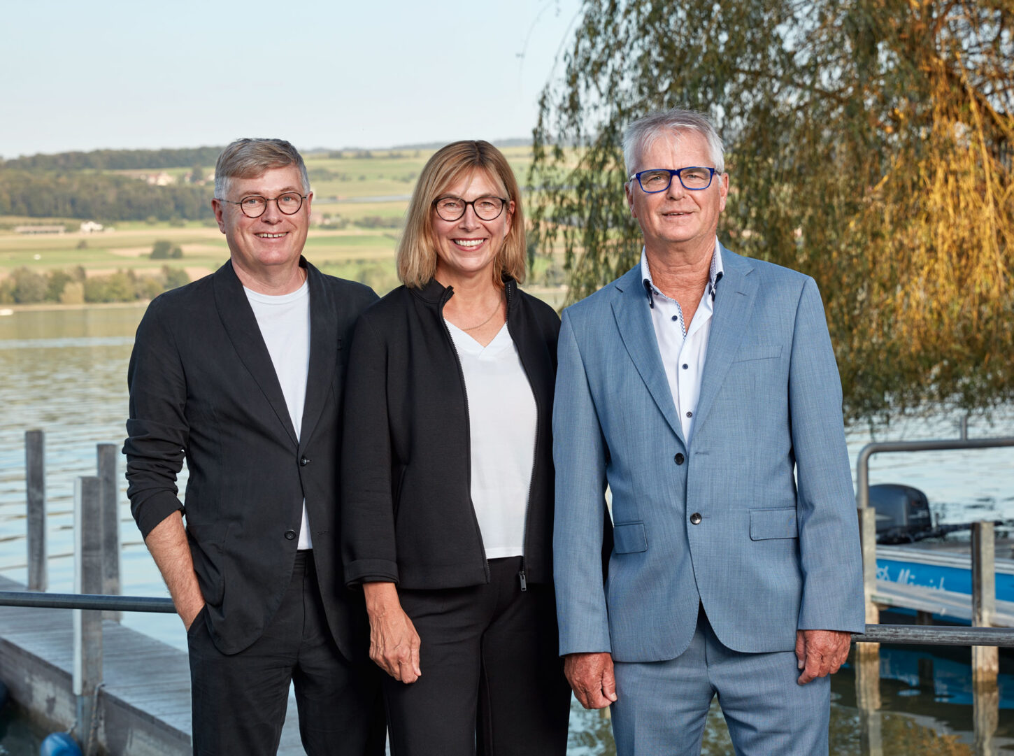 Joe Birchmeier, VRP Stadttheater Olten und Präsident der Kulturstiftung aus Starrkirch-Wil, Irene Näf-Kuhn, Musikerin, Kantonsschullehrerin und Inhaberin der Pianolounge aus Erlinsbach SO sowie Jürgen Sahli, Journalist aus Tennwil, stehen nebeneinander auf einem Holzsteg vor dem Hallwilersee.